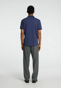 Polo en navy à manches courtes et col, associé à un pantalon gris ample. Design simple sans motifs ni accents visibles.
