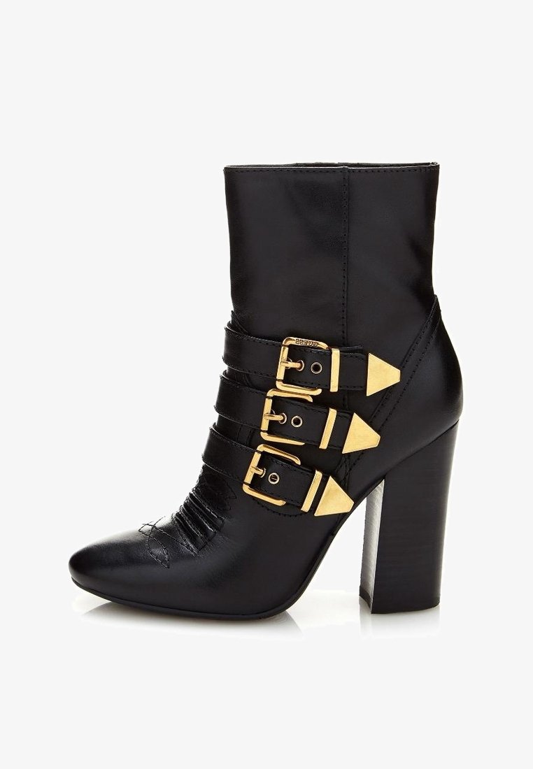 Bottine en cuir noir avec trois boucles dorées, bout pointu et talon haut épais.