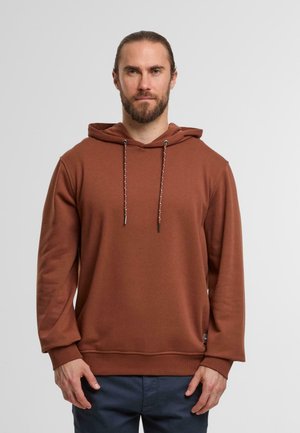 Brown hooded sweatshirt with a soft texture, featuring contrasting drawstrings and ribbed cuffs, worn over navy pants.