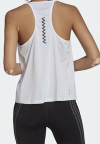 Vit atletisk linne med racerback-design, tillverkad av andningsbart mesh-tyg, med en zickzack-detalj på ryggen.