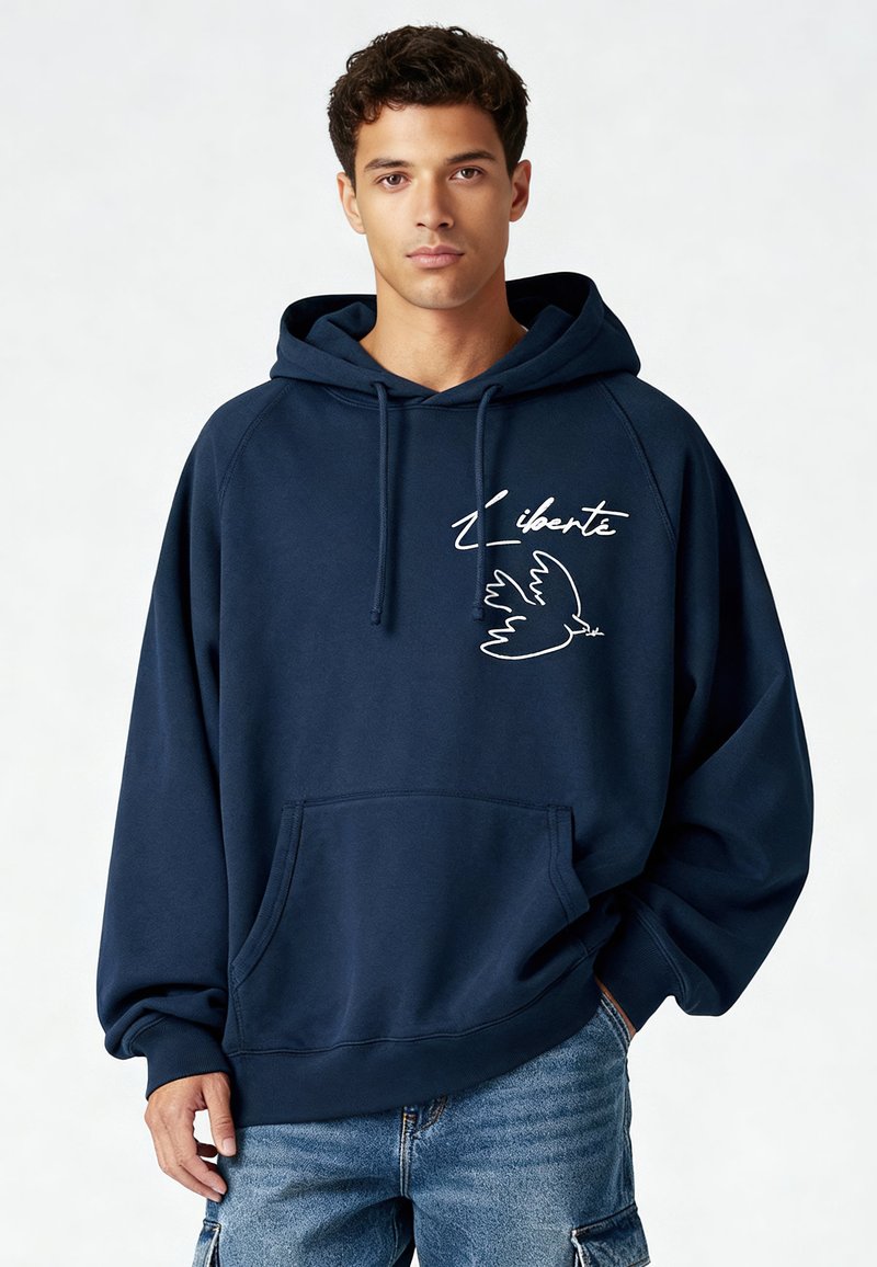 Sweat à capuche bleu marine avec une poche avant, présentant le texte blanc "Liberté" et un motif d'oiseau. Confectionné en tissu doux et texturé avec une coupe décontractée.
