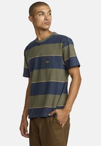 Horizontal striped t-shirt in green, navy, and beige; features a chest pocket and logo patch; made of soft cotton material.