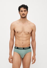 Menns grønne bomullsboxer med en svart PUMA-logo i livet. Har en tettsittende passform og glatt tekstur, designet for komfort og støtte.