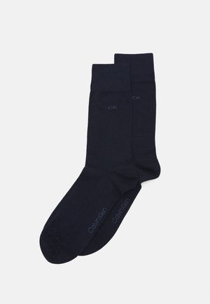 Calcetines de algodón azul marino con puños acanalados, con el logotipo en relieve "CK" y la marca "Calvin Klein" en la punta. Diseño sencillo y uniforme.