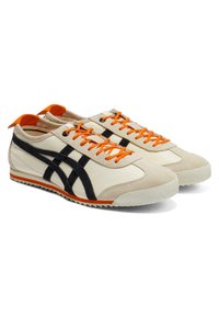 Kremowe sneakersy z czarnymi zamszowymi akcentami, pomarańczowymi sznurówkami i dopasowanym uchwytem na pięcie. Teksturowana gumowa podeszwa z wzorowanym gripem.