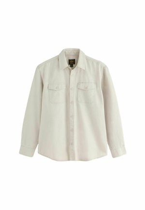 Beige skjorte med lange ærmer, knapper, krave og to forlommer med klap, vist mod en hvid baggrund.