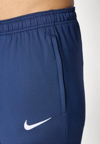 Mornarsko modri atletski kratki hlače z elastičnim pasom, ki imajo bel Nike logotip in stranji žep. Gladek, lahek material.