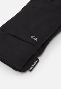 Čierna látková rukavica so tesným strihom, obsahujúca malé sivé logo a označenie "QUIKSILVER" na manžete. Mäkko textúrovaný materiál.