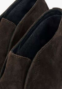 Hnědé kožené kotníkové boty s hladkým povrchem, s nízkým střihem a minimalistickým designem. Prošívání podél okrajů.