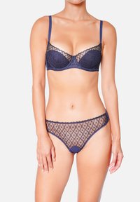 Ensemble de lingerie bleu marine comprenant un soutien-gorge en dentelle avec armatures et des détails transparents, associé à une culotte transparente assortie, tous deux ornés d'accents à motifs floraux.