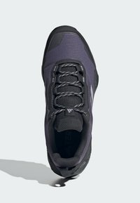 Svart och lila löparskor med ett strukturerat meshupp som har en förstärkt tåspets och reflekterande snör detaljer. Hållbar gummisula.