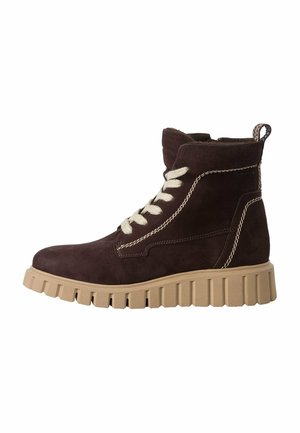 Braune Wildleder-Ankelboots mit einer stabilen beige Gummisohle, die cremefarbenen Schnürsenkel und kontrastierende Nähte aufweisen. Mit einer Zuglasche an der Rückseite.