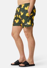 Zwemshorts van groene stof met een patroon van gele rubberen eenden. Inclusief een tailleband met trekkoord en witte logodetail. Zwarte sliders zichtbaar.