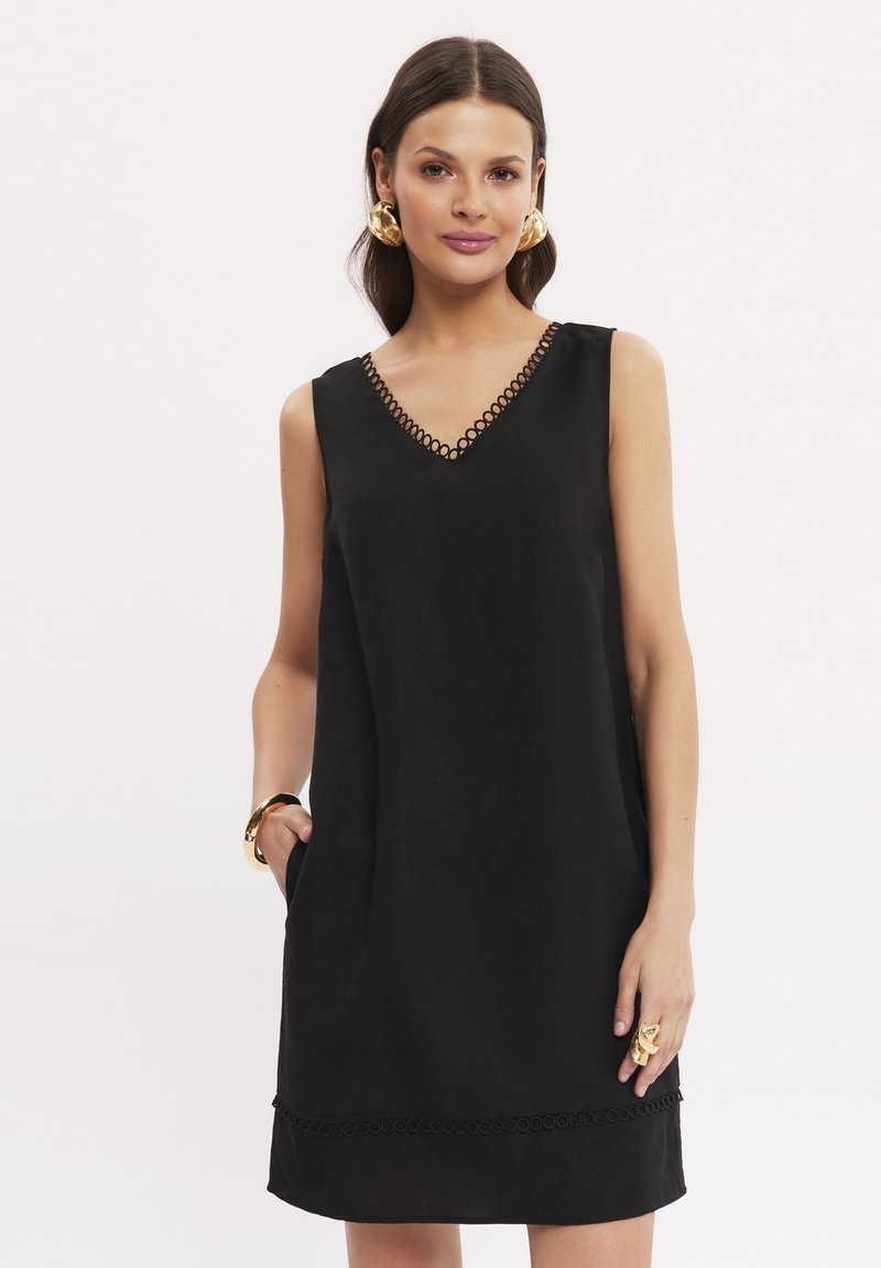 Czarna sukienka bez rękawów z dekoltem w kształcie litery V, z okrągłym koronkowym wykończeniem wokół dekoltu i dołu, oraz bocznymi kieszeniami. Gładka faktura materiału.