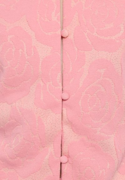 Pink cardigan featuring a rose pattern, textured fabric, and small buttons down the front. Subtle shimmer adds visual interest.