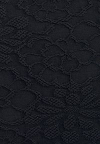Tissu en tricot noir présentant des motifs floraux et géométriques en relief, avec des textures et des formes variées sur l'ensemble de la surface.