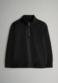 Mustapuluinen neule, joka on valmistettu pehmeästä kankaasta. Siinä on korkea kaulus, puolipitkä vetoketju sekä ribbaustekniikalla tehdyt hihansuut ja helma. Yksinkertainen muotoilu.