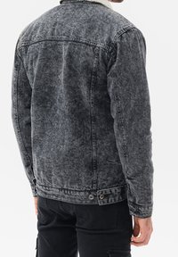 Giubbotto in denim grigio con colletto in shearling, con una finitura testurizzata, cucitura al giromanica e dettagli con snap laterali.