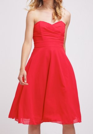 Rode, strapless, A-lijn jurk met een getailleerde lijf en een uitlopende rok. De stof lijkt lichtgewicht en soepel, met subtiele plooien op de borst.