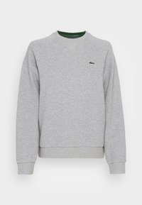 Grå sweatshirt med rundad halsringning, ribbad ärmslut och nederkant. Uppenbart grönt Lacoste-logotyp på bröstet. Mjuk, strukturerad tyg.