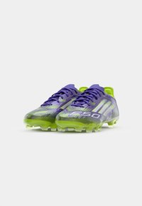 Purple and green soccer cleats with a sleek design, featuring a textured upper, contrasting stripes, and molded studs for traction.