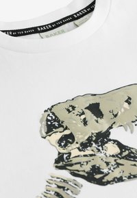 Weißes Baumwoll-T-Shirt mit einem großen, grafischen Druck eines Skeletts in Schwarz-, Grau- und Beigetönen. Etikett im Kragen sichtbar.