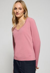 Långärmad rosa t-shirt med v-ringning, tillverkad av mjukt material, med en avslappnad passform och diskret logotypdetalj vid fållen.