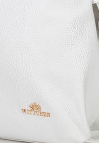 Weiße Leder-Handtasche mit strukturiertem Finish, ausgestattet mit einem goldenen "WITTCHEN"-Logo und einer strukturierten Form mit weichen Kanten.