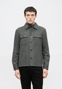 Sacou gri cu carouri, cu nasturi în față și buzunare cu clapetă, cu guler și mâneci lungi, confecționat dintr-un material texturat.