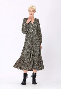 Robe midi à imprimé floral avec manches longues et col en V, présentant une jupe fluide à volants. Fond sombre avec des motifs multicolores, agrémentée de bottes noires.