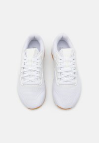 Λευκά αθλητικά παπούτσια με αναπνέον ανώτερο διχτυωτό υλικό, επίπεδες κορδόνες και υφή σόλας με γυμνό καουτσούκ. Στρογγυλή σχεδίαση στη μύτη.