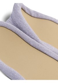 Närbild av beige innersulor med ljuslila glittriga tygkanter som visar textur och mjuka dämpningsdetaljer.