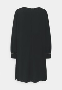 Robe noire à manches longues avec col rond et bordure subtile en perles blanches aux poignets, vue de dos sur fond blanc.