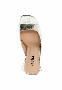 Sandale à talons argentés avec une finition brillante et texturée ressemblant à de la peau de serpent. Design à bout carré et côtés ouverts. Semelle intérieure couleur crème avec logo.