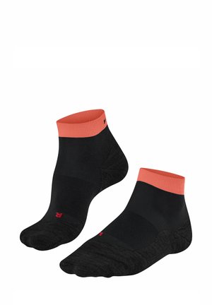 Schwarze Knöchelsocken mit einem korallfarbenen Bündchen, ausgestattet mit verstärkten Fersen- und Zehenbereichen sowie einem kleinen roten Logo an der Seite. Weiches, dehnbares Material.