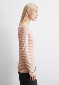 Striped long-sleeve shirt in soft pink and cream fabric. Fitted design, round neckline, and extended cuffs at the wrists.