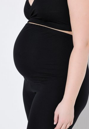 Černý těhotenský top a legíny, vyrobené z měkké tkaniny, přiléhavý design s elastickým páskem, zobrazující zaoblený tvar bříška.