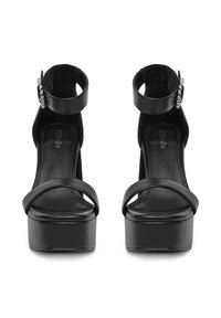 Sandale negre cu platformă, cu un finisaj lucios, având două curele înguste și o curea cu cataramă la gleznă. Tocul este gros și stabil.
