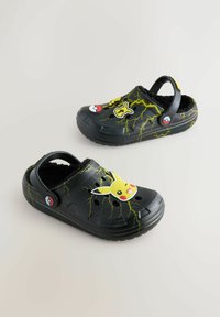 Zwarte klompen met een fuzzy binnenkant, versierd met Pikachu en Pokéball ontwerpen. Gedecoreerd met gele bliksempatronen; gemaakt van plastic.