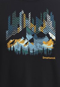 Zwarte T-shirt met een kleurrafische afbeelding van bergen, bomen en zigzagpatronen in teal, blauw, oranje en wit. Inclusief het "Smartwool" logo.