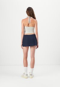 Gray halter top and navy mini skirt, paired with white socks and sneakers. The top features a tie at the back, and the fabrics appear smooth.
