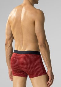 Czerwone slipki z granatowym pasem, ozdobione małym białym wzorem w kropki. Wykonane z gładkiego, elastycznego materiału dla wygody.