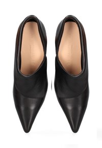Scarpe in pelle nera con punta affilata e superficie liscia, caratterizzate da un design inclinato e un tacco basso, che mettono in mostra uno stile minimalista.