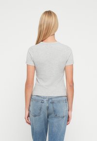 Γκρι κοντομάνικο μπλουζάκι με εφαρμοστή σχεδίαση, κατασκευασμένο από απαλό βαμβάκι. Συνδυάζεται με ψηλόμεσο τζιν μπλε χρώματος, με τσέπες στο πίσω μέρος.