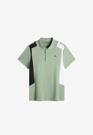 Jasnozielona koszulka polo z czarnymi i białymi blokami kolorystycznymi na ramionach, krótkimi rękawami, kołnierzykiem oraz małym logo na piersi.