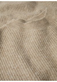 Pull beige en maille avec une texture côtelée, doté d'un col rond et d'un tissu doux. Le matériau semble chaud et confortable.