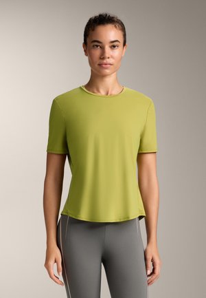 Tricou sportiv de culoare verde lime, cu mâneci scurte, gât rotund, textură netedă și croială relaxată, asortat cu colanți gri mulați.