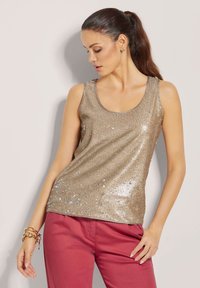 Gouden glittertop met een ronde hals, gemaakt van een textuurstof; heeft een rechte snit en is gestyled met roze broek.