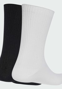 Čierne a biele bavlnené ponožky s rebrovanou textúrou a strednou dĺžkou po lýtko. Čierna ponožka je naľavo a biela ponožka je napravo.