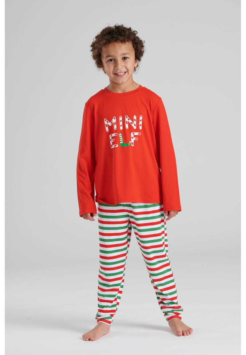 Camisa roja de manga larga con el texto "MINI ELF" en blanco y verde, combinada con pantalones blancos que tienen rayas rojas y verdes.
